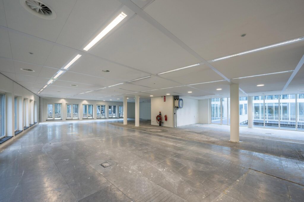 Leeg en licht kantoorpand aan de De Cuserstraat met grote ramen en systeemplafond.